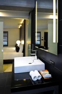 a bathroom with a white sink and a bedroom at Hercor Hotel - Urban Boutique in Chula Vista