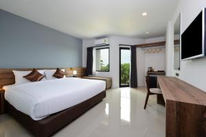Dormitorio con cama, escritorio y TV en The Chill at Krabi Hotel, en Krabi