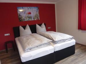 two beds in a bedroom with a red wall at Gästehaus Erle in Memmingen