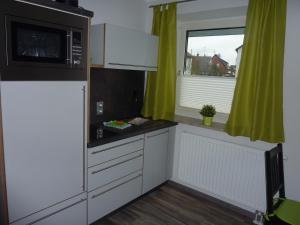 a kitchen with white cabinets and a microwave and a window at Gästehaus Erle in Memmingen