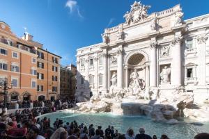 a crowd of people standing around a fountain in front of a building at Trevispagna Charme Apartment Autonomous in Rome