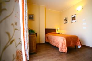 a bedroom with a bed with an orange bedspread at Hotel Ristorante Al Duca in Atessa