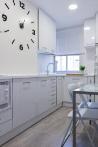 une cuisine avec des placards blancs et une horloge murale dans l'établissement Apartamento del Sueño con Aire Acondicionado, à Logroño