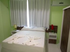 a bedroom with a bed with white sheets and a window at Hotel Letiva Arco in Sobral