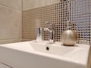 a bathroom sink with a faucet and a basket on it at Apartament Starogdański 7 in Gdańsk