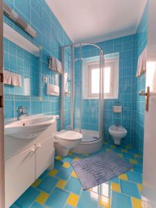 a blue tiled bathroom with a sink and a toilet at Garni Toni in Ortisei