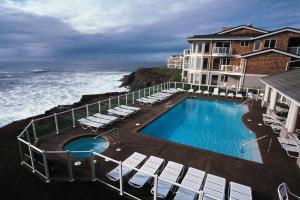 a hotel with a swimming pool and chairs and the ocean at WorldMark Depoe Bay in Depoe Bay