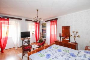 um quarto com uma cama, uma televisão e cortinas vermelhas em Apartment Johanna em Opatija
