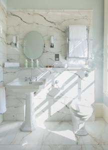 a white bathroom with a sink and a mirror at The White House in Burnham Market