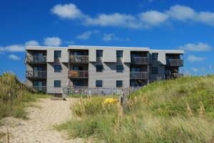 a building on the beach next to a sandy beach at Admirals View III by KEES Vacations in Kill Devil Hills