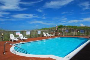 a swimming pool on a deck with chairs and a table at Admirals View III by KEES Vacations in Kill Devil Hills