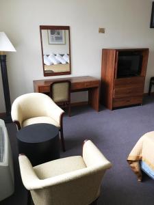 Zimmer mit 2 Stühlen, einem Schreibtisch und einem TV in der Unterkunft Village Motel in Ellenville