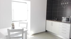 a kitchen with white cabinets and a table and a microwave at Casa do Rio in Alcácer do Sal