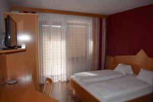 Schlafzimmer mit einem Bett, einem TV und einem Fenster in der Unterkunft Pension Seeblick in Mörbisch am See
