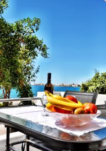 イエラペトラにあるOn The Beachのワイン1本とテーブルの上にフルーツを盛り付けたボウル