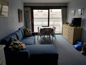科克赛德Zonnig Appartement met Zeezicht的客厅里有一张蓝色的沙发和一张桌子