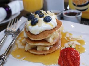 a stack of pancakes with a strawberry on a plate at The Ambassador Townhouse in Southport