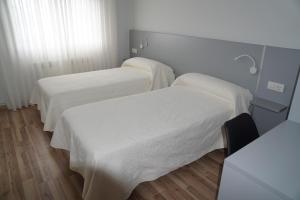 a hotel room with two beds and two lamps at Pension Perez in Portomarin