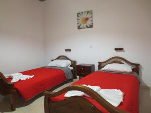 a bedroom with two beds with red sheets at Sidari Studios in Sidari