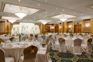 a banquet hall with white tables and chairs and chandeliers at Corniche Hotel Sharjah in Sharjah +37 photos