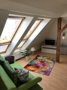 a living room with a green couch and windows at Liebevoll eingerichtete Ferienwohnung im DG in Zwenkau