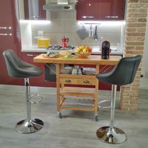 kuchnia z 2 stołkami barowymi i stołem z jedzeniem w obiekcie CaMagnolia Apartment w mieście Montegrotto Terme +29 zdjęć