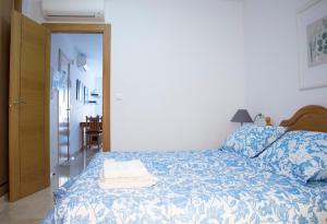 a bedroom with a bed with a blue and white comforter at Apartamentos Turísticos Fercomar in Nerja