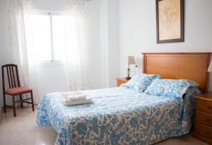 sypialnia z łóżkiem z niebieskim kocem i krzesłem w obiekcie Apartamentos Turísticos Fercomar w mieście Nerja +29 zdjęć