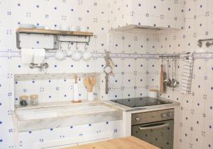 a kitchen with white tiled walls and a sink at Casa do Mercado in Aveiro
