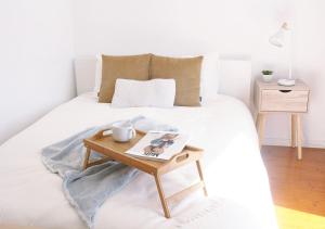 a white bed with a wooden coffee table on it at Casa do Mercado in Aveiro