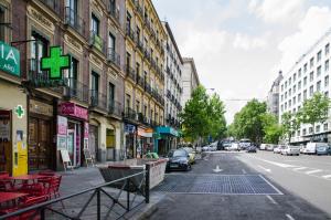 una calle urbana vacía con edificios, mesas y coches en Minty Stay - Atocha 4 BD en Madrid