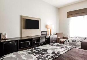 a hotel room with a bed and a desk with a television at Sleep Inn & Suites Hannibal in Hannibal