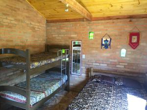 コンセイサオン・ダ・イビティポカにあるChalé Ibitiのレンガの壁に二段ベッド3組が備わる客室です。