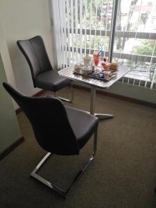 Hostal Costa De Marfil Suites & Apartamentos في كوتشابامبا: كرسيين وطاولة في غرفة مع طاولة وأغطية طاولة