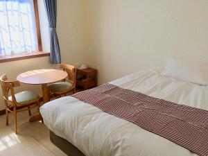 Schlafzimmer mit einem Bett, einem Tisch und einem Fenster in der Unterkunft Oli Oli Guesthouse in Shimoda