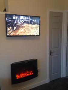 telewizor z płaskim ekranem wiszący na ścianie z kominkiem w obiekcie Kevara Self-Catering w mieście Finstown