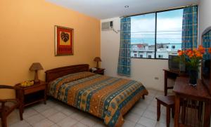 1 dormitorio con cama, escritorio y ventana en Hostal Solar Del Puerto en Machala