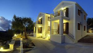a large white building with lights in front of it at Adastra Ithaca Luxury Suites in Vathi