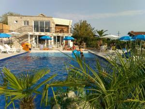 a swimming pool with blue umbrellas and a house at Luštica Apartments in Luštica