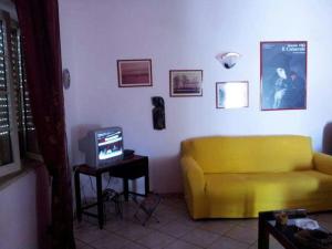 a living room with a yellow couch and a tv at Villetta al mare in Marausa
