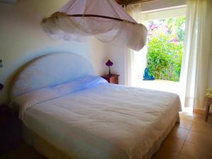 a bedroom with a white bed with a window at Villa LES TILILIS - BELLE VILLA DE 300 M2 SITUEE AU CALME AVEC GRANDE PISCINE ET VUE MONTAGNE in Petit-Bourg