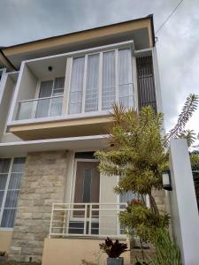 une maison avec des fenêtres blanches et un arbre dans l'établissement Villa Keluarga Batu, à Batu