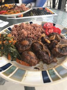 a plate of food with meat and rice on a table at Drifters@One Mile in Negril