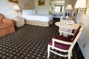 a hotel room with a bed and a table and chair at Anaheim Carriage Inn in Anaheim +20 photos