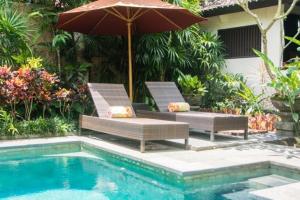 two chairs and an umbrella next to a swimming pool at Lily Lane Villas in Ubud