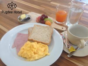 a plate of food with eggs and toast and a cup of coffee at Pugdee Hotel in Lang Suan