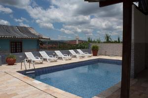 una piscina con sillas blancas y un grupo en Maison Delfino Flat, en Gravatá