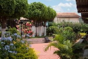 un jardín con flores y árboles y un banco en Maison Delfino Flat, en Gravatá