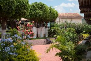 a garden with flowers and trees and a bench at Maison Delfino Flat in Gravatá