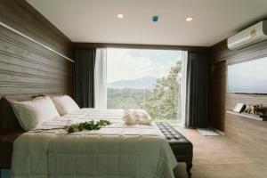 a bedroom with a large bed with a large window at Urban Maerim in Mae Rim